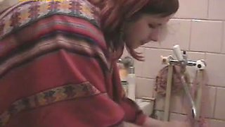 Margo washes her face in a bathroom and flashes her pussy